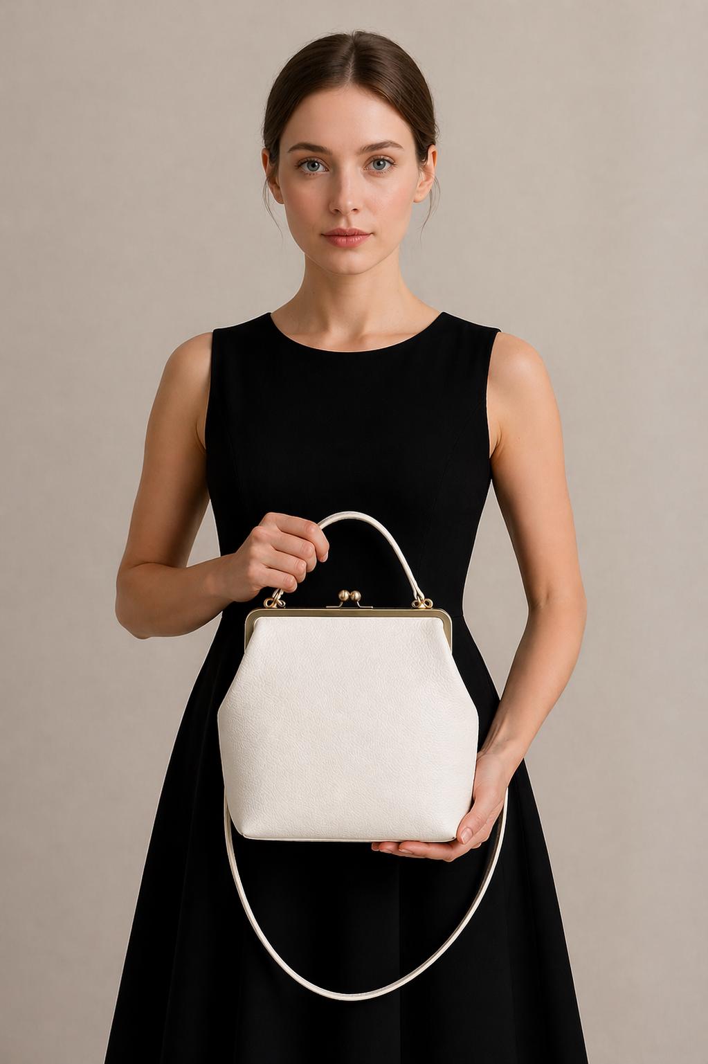 Könnte beinhalten: Eine weiße, strukturierte Handtasche mit goldenem Verschluss und Griff. Die Tasche hat einen langen, dünnen Riemen und eine strukturierte Oberfläche. Die Frau im Bild trägt ein schwarzes Kleid.